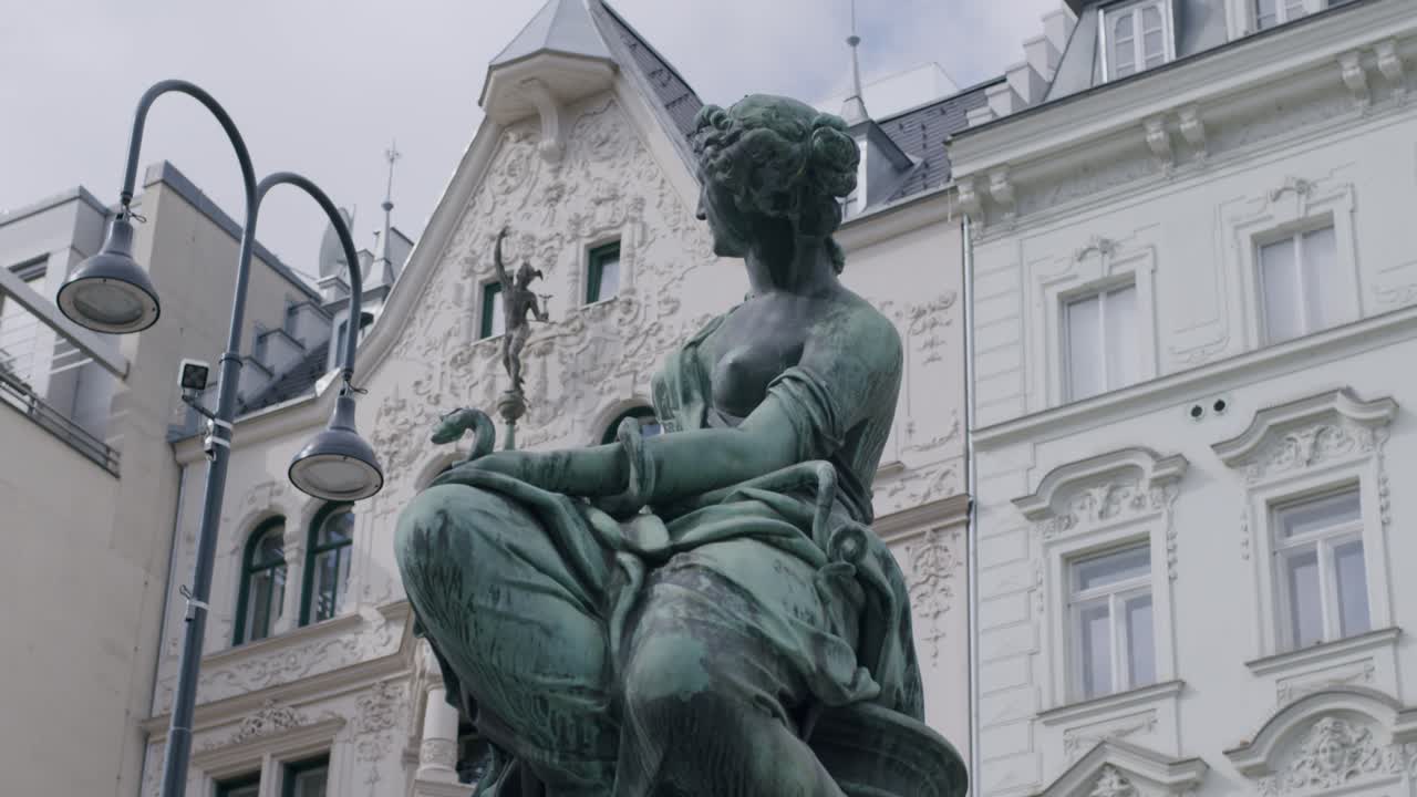Elegant bronze statue of a seated woman in Vienna's historic Donnerbrunnen square
