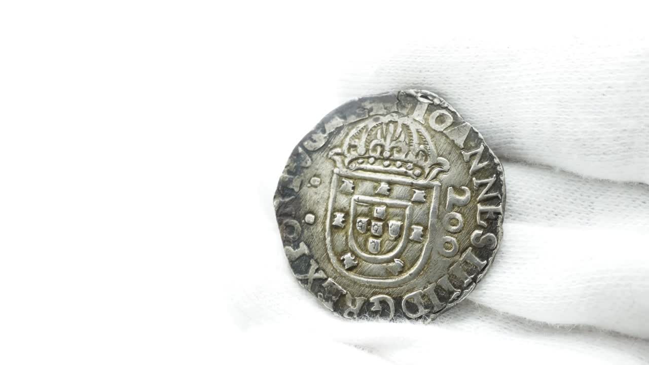 нумизматик в белых перчатках смотрит на старую монету 38