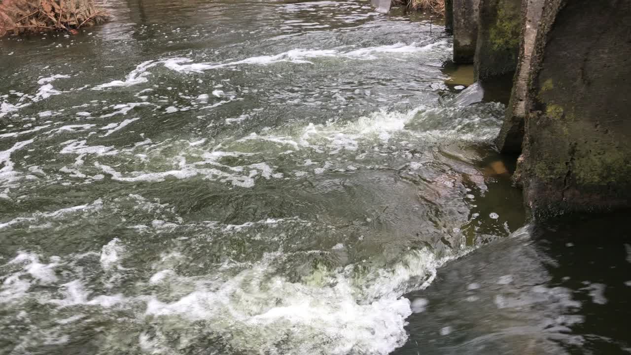 Streams of water flow through concrete sewers. Polluted body of water in the park.