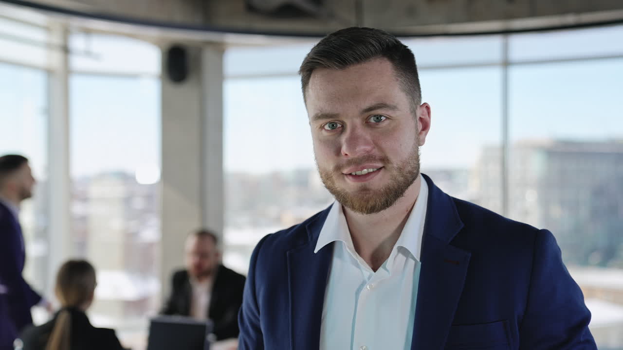 Portrait of a smiling entrepreneur standing in the office. Close up. Active teamwork at the desk at background.