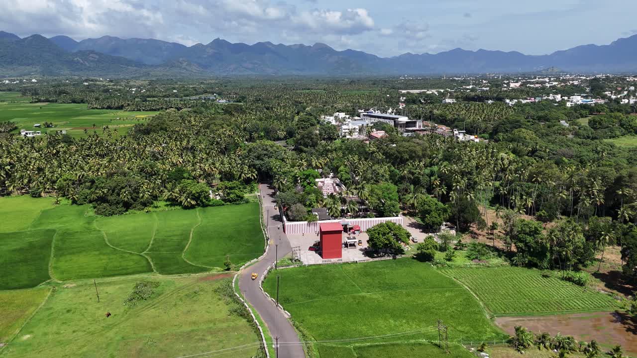 This high-angle shot symbolizes the cultural heart of rural India. The temple represents tradition and community, set against a backdrop of vast bright green paddy fields and coconut palm groves