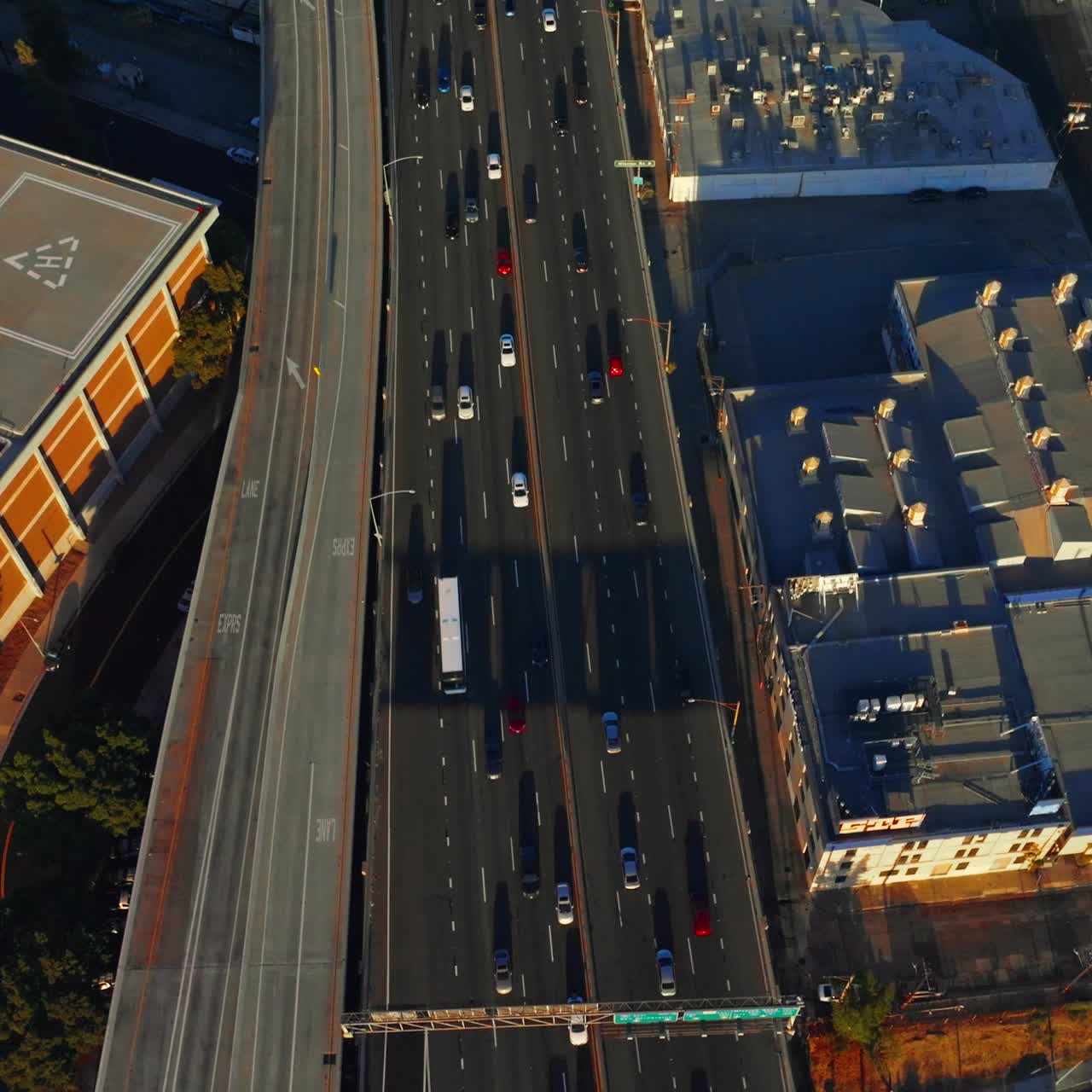 Flight above the overhead road with lots of cars moving by. Los Angeles roofs with helicopters on. Aerial view