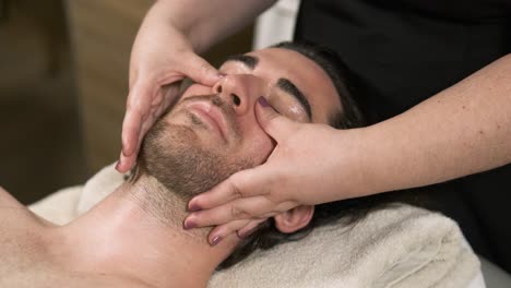 beautician performing a soothing facial massage for a man in a tranquil wellness center