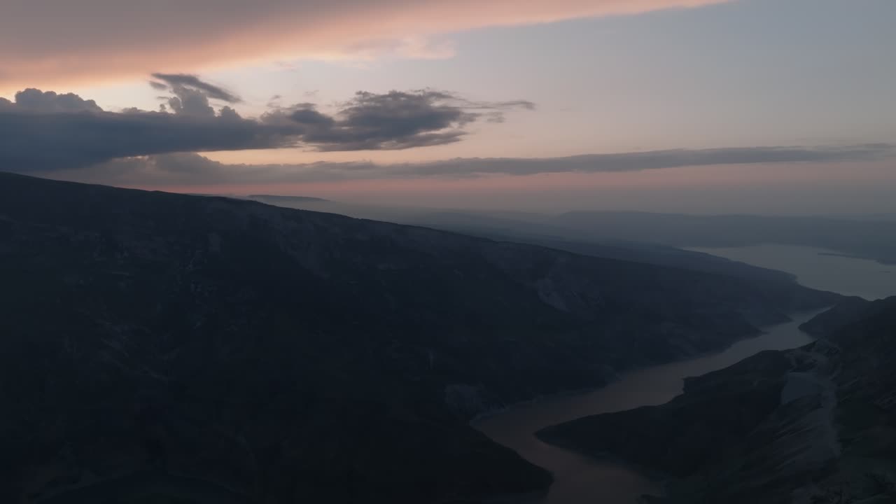 Aerial footage of the main viewpoint of Sulak Canyon at sunset, with dramatic clouds and a winding river below, in Dagestan, Russia, Caucasus mountains