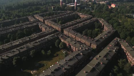 fotografía aérea del histórico asentamiento de trabajadores de nikiszowiec en europa central, con una fábrica y chimeneas en el fondo, en un soleado día de verano, 4k