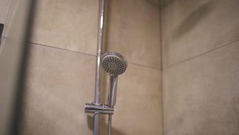 a slow-moving shot captures a sleek showerhead in a luxury hotel bathroom, showcasing the modern design and upscale amenities that offer a premium guest experience