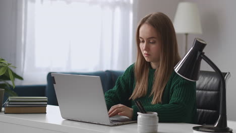 Una-Mujer-Independiente-Está-Trabajando-Con-Un-Cuaderno-En-La-Oficina-De-Casa-Sentada-En-La-Mesa-Y-Escribiendo-En-El-Teclado-Retrato-Tomado-En-Interiores-Trabajo-En-Línea-Por-Internet