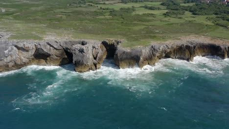 rocky limestone seacliffs eroded away, blue water of bufones de pria asturias spain, aerial