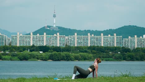 fit caucasian yoga teacher practice different poses exercising side plank, downward dog asana, doing reverse plank on grassy meadow by the river in seoul, south korea