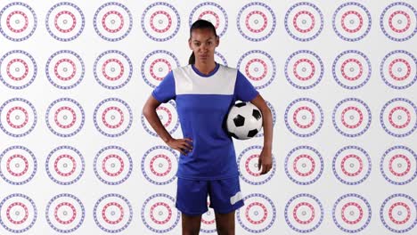 African-american-female-soccer-player-holding-a-ball-against-stars-on-multiple-spinning-circles