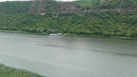 barco estacionado en la orilla del río que se encuentra entre dos altas colinas completamente verde