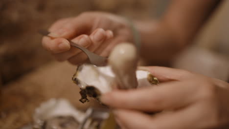 close-up of hands extracting and eating fresh oysters