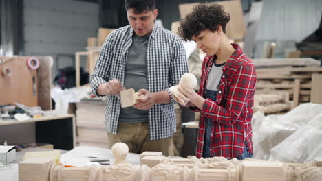 Two People Working on Wooden Furniture Parts in a Workshop