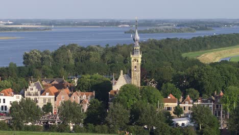 beautiful aerial orbit shot of the church of veere in the province of zeeland, netherlands, with old buildings and the ocean and bay in the background