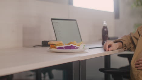 Cerca-De-Una-Mujer-Embarazada-Que-Trabaja-Comiendo-Pepitas-Durante-El-Almuerzo-De-La-Oficina