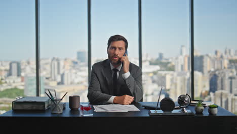 hombre corporativo hablando por teléfono móvil en la oficina panorámica. llamada del gerente exitoso