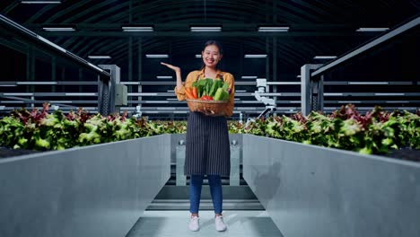 full body of asian female farmer with vegetable basket showing open hand palm while standing in smart farm