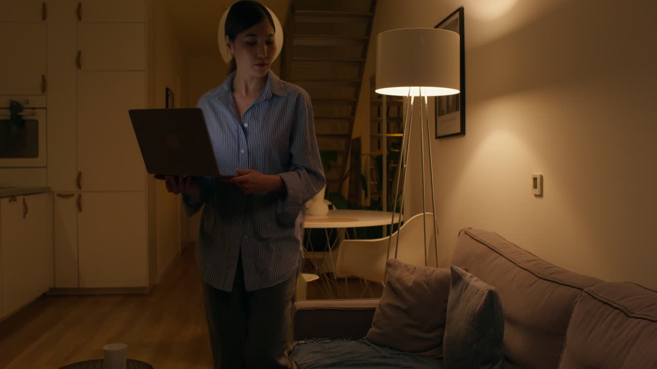 Woman working on laptop in living room at night