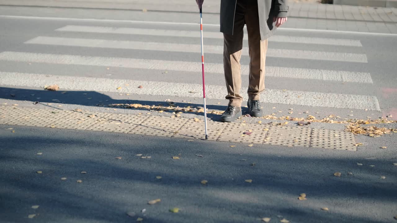 hombre con discapacidad visual cruzando la carretera con su palo con la ayuda de la acera táctil para peatones para discapacitados visuales en la ciudad.