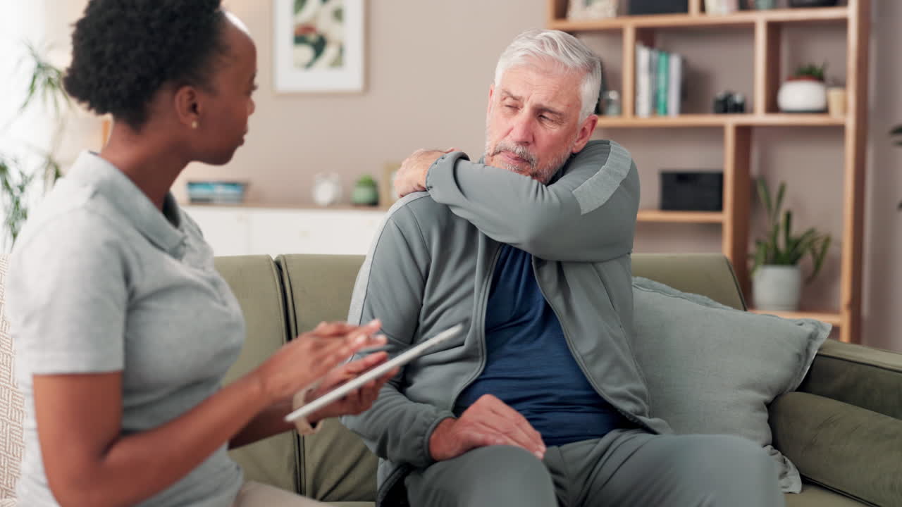 Senior man receiving medical consultation for shoulder pain at home