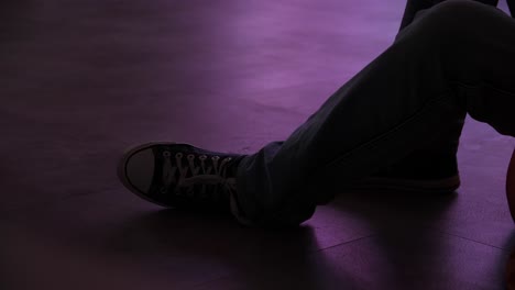 person sitting on the floor with dark-colored shoes and jeans