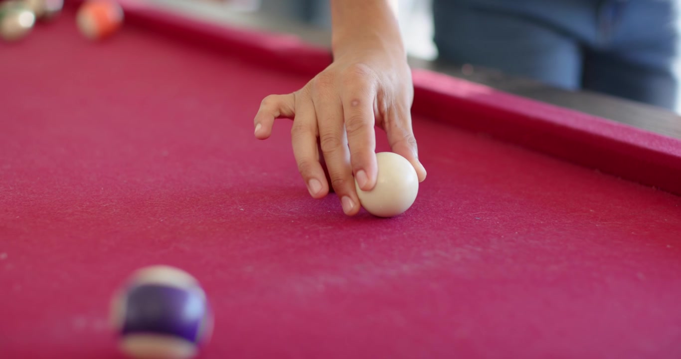 African American couple preparing shot at red pool table, man holding cue, woman moving cue ball