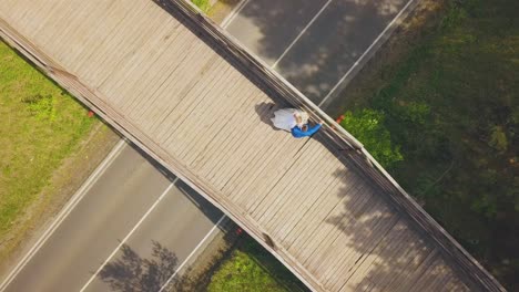 newly-wedded-couple-at-railing-on-wooden-bridge-aerial-view