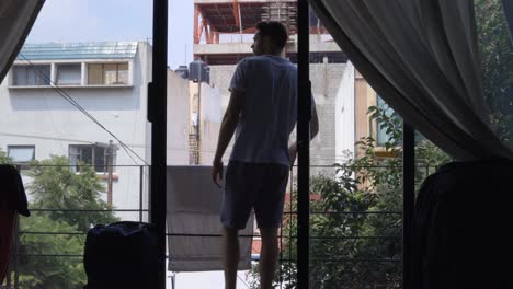 Young-male-man-in-holiday,-on-his-hotel-airbnb-balcony,-Mexico-Neighbourhood