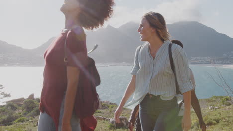 grupo de jóvenes amigos caminando de pie en los acantilados por la costa y mirando la hermosa vista