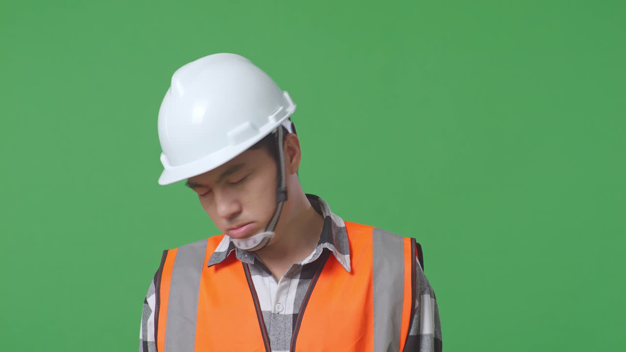 Close Up Of Asian Male Engineer With Safety Helmet Having A Headache While Working In The Green Screen Background Studio