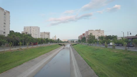 the bahlui river in iasi runs through an urban area, framed by grass and distant buildings