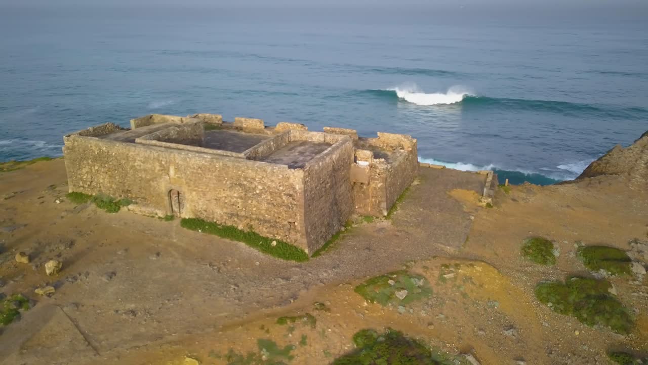 vista aérea del fuerte de guincho en la costa de lisboa con algunas olas rompiendo en el fondo, portugal