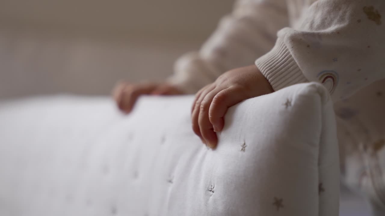Primo piano delle manine di un neonato che stringono un tessuto bianco a stelle