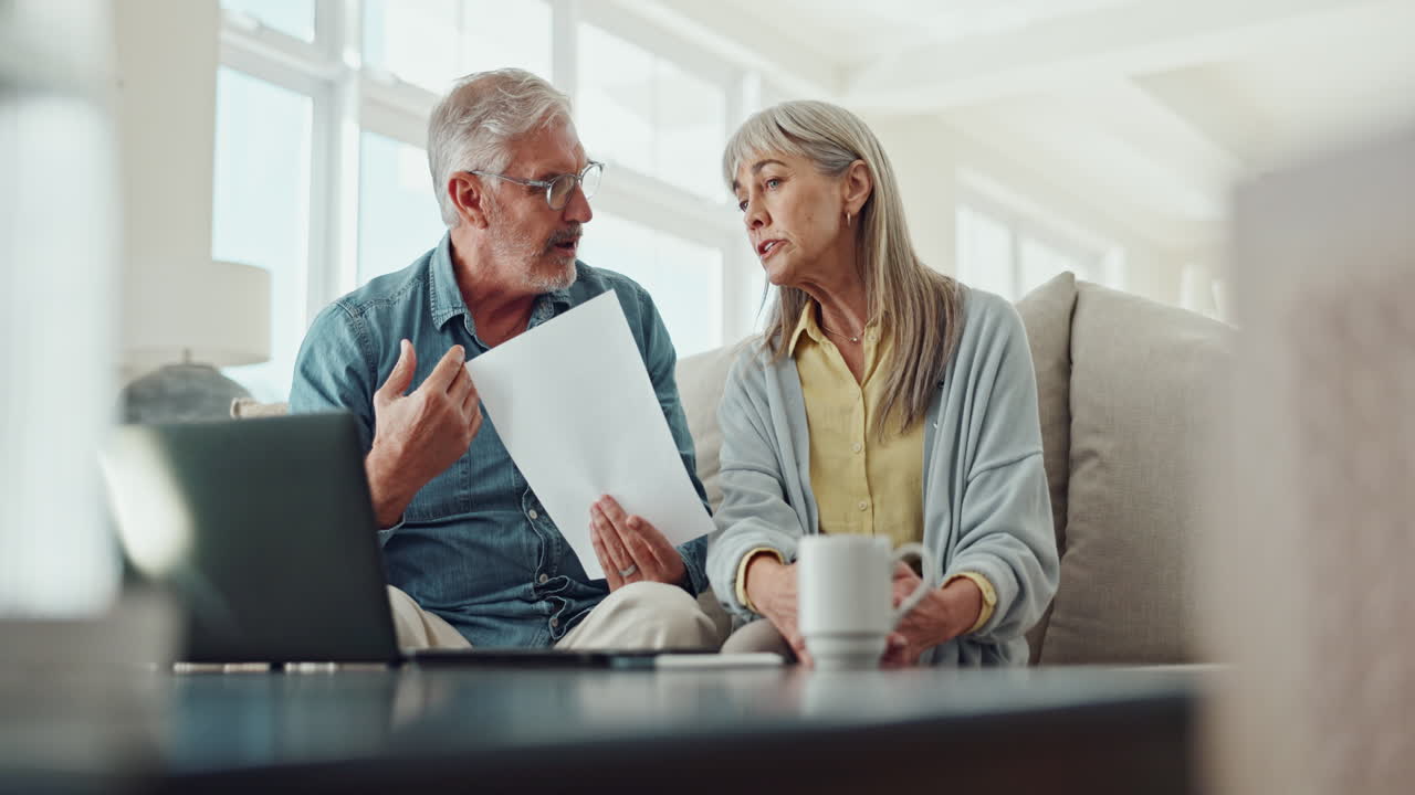una pareja de ancianos discutiendo finanzas en casa.