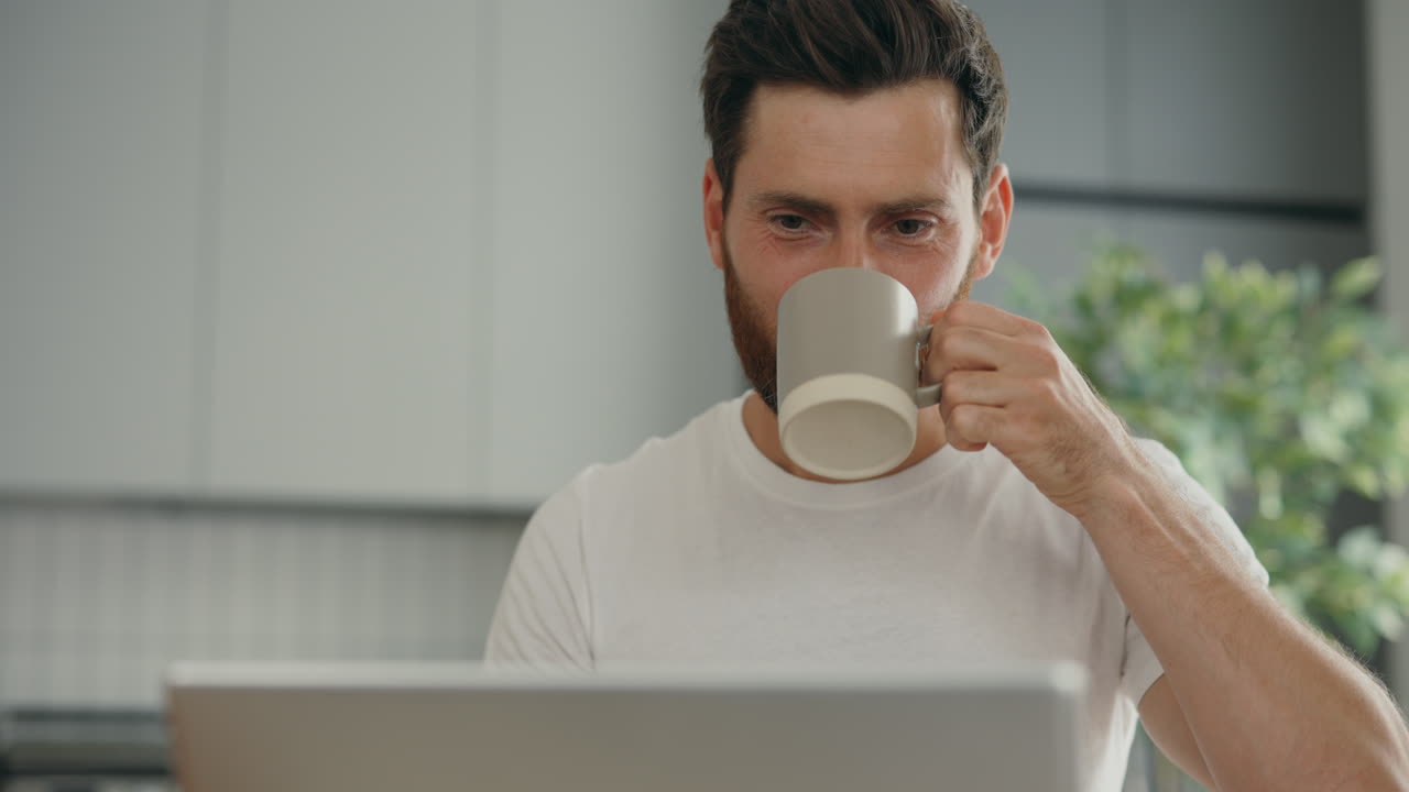 Man working from home drinking coffee and using laptop