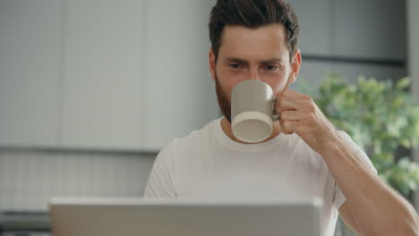 man working from home drinking coffee and using laptop