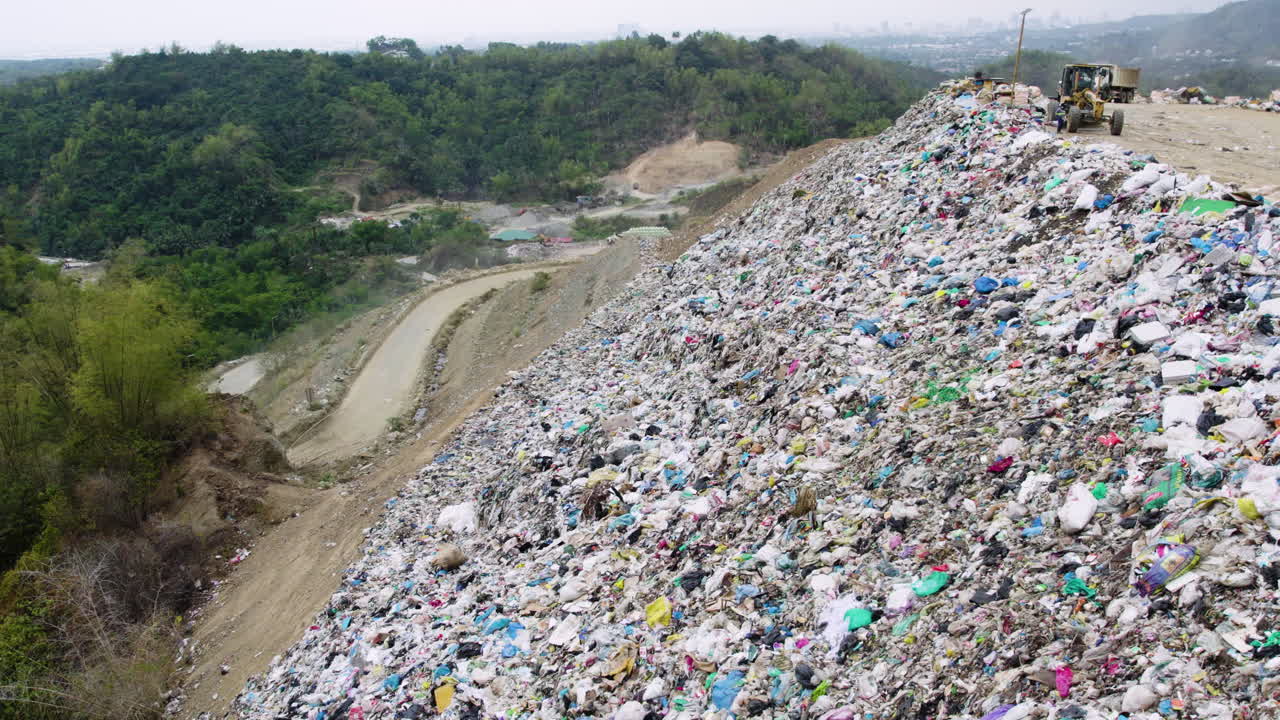 tomada de un avión no tripulado de un vertedero con camiones y tractores que manejan la basura, destacando los esfuerzos de eliminación y reciclaje de residuos