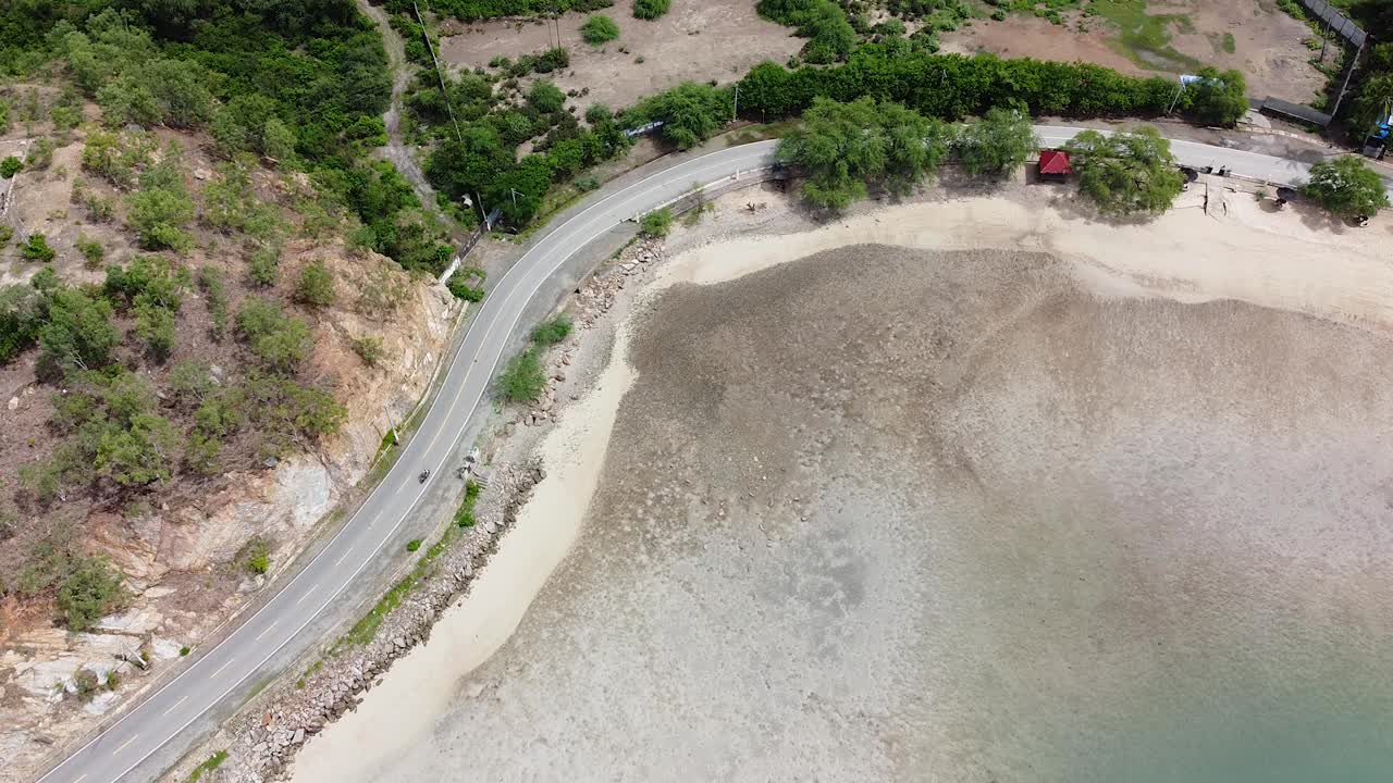 Aerial birds eye view of scooter traffic traveling along coastal road next to ocean in capital city Dili, Timor-Leste in Southeast Asia