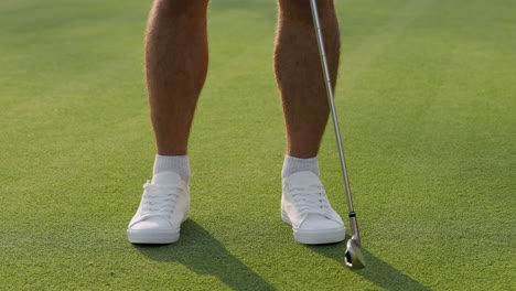 person preparing to putt golf ball