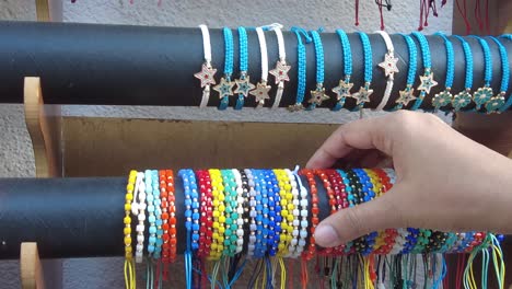 close up of a hand picking out colorful beaded bracelets