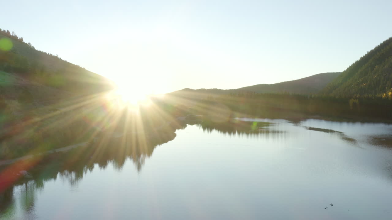 4K aerial drone footage of a sunrise over a lake in the Rocky Mountains of Colorado in the autumn or fall with changing aspen trees