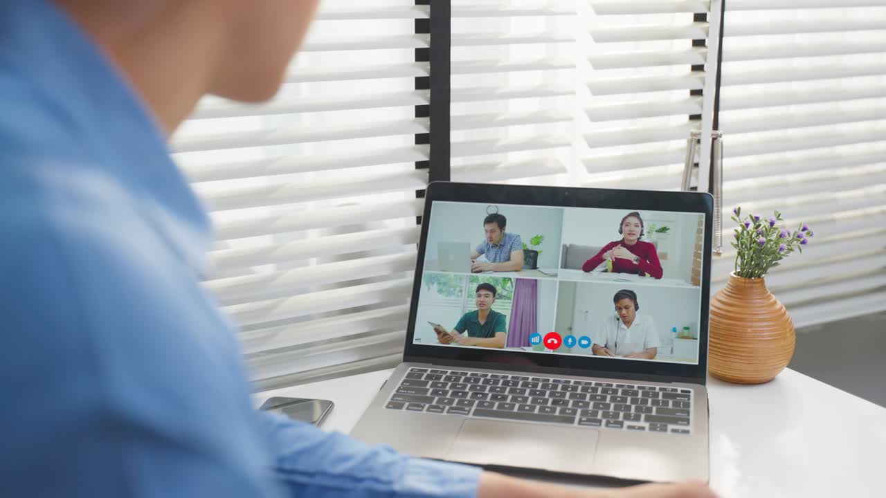 アジアのビジネスマンがオフィスの同僚とノートパソコンでビデオコールをします 魅力的なハンサムなプロの男性従業員がテーブルに座って会議や企業の職場でのブレインストーミングに取り組んでいます