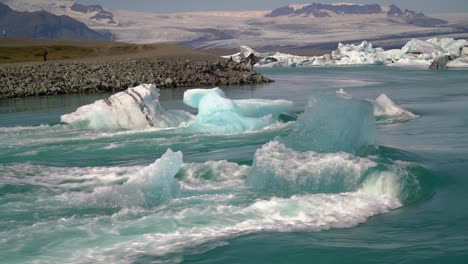 Blaugrüne-Eisstücke,-Die-Im-Flussbett-Stecken,-Scheinen-Sich-An-Das-Flusswasser-Zu-Lehnen