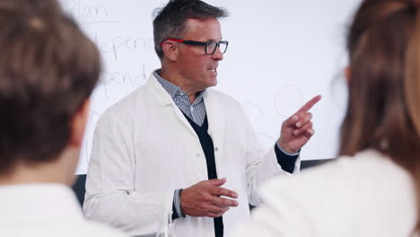 male high school science teacher standing in front of whiteboard teaching lesson