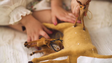 Cámara-Lenta-De-Niña-En-Vestido-De-Navidad-Jugando-Con-Figuritas-De-Juguete-De-Ciervo---Primer-Plano