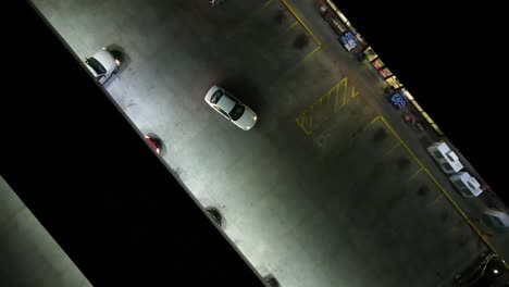 toma aérea de un dron de personas que van y vienen en una gasolinera por la noche