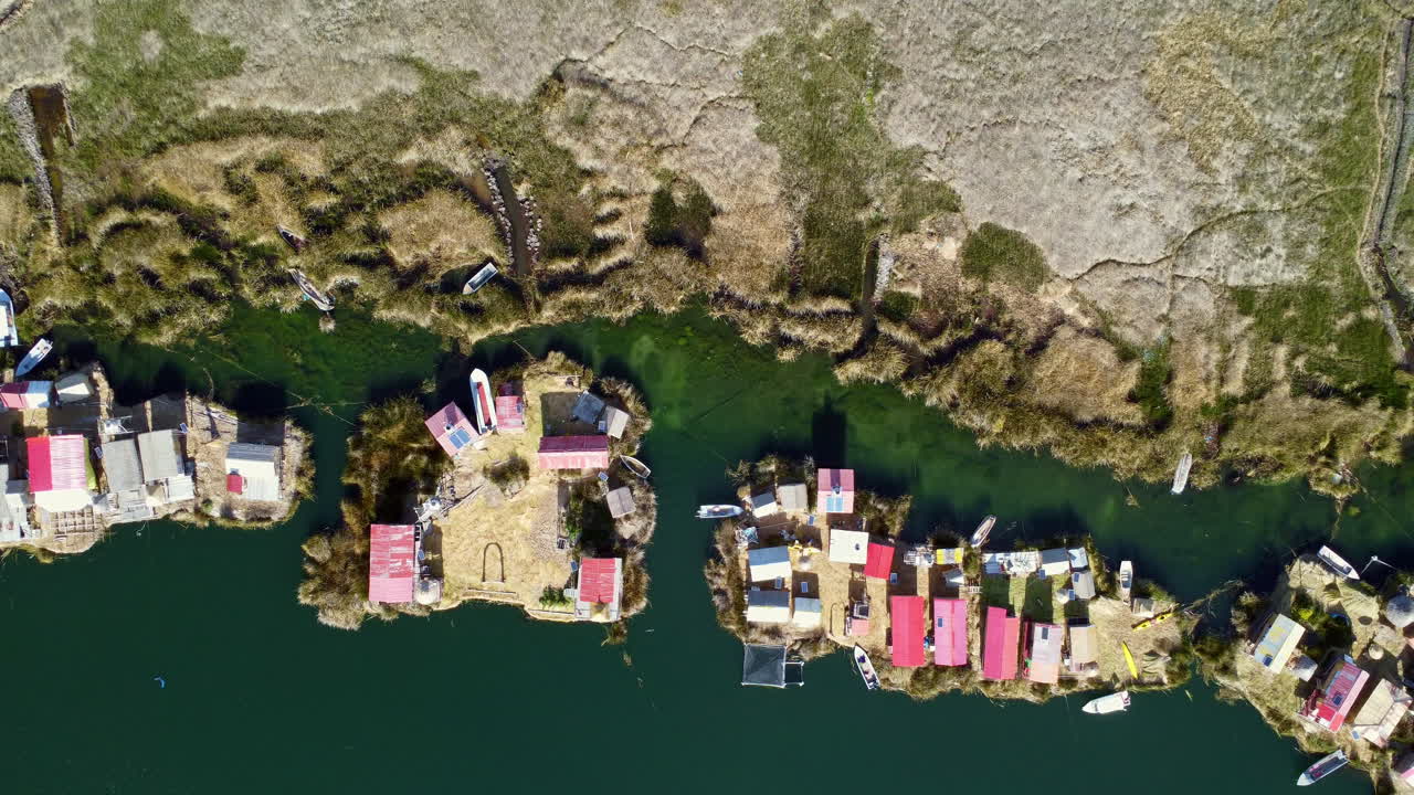 Drone top down ascend above Uros Island floating homes on Lake Titicaca on banks of land
