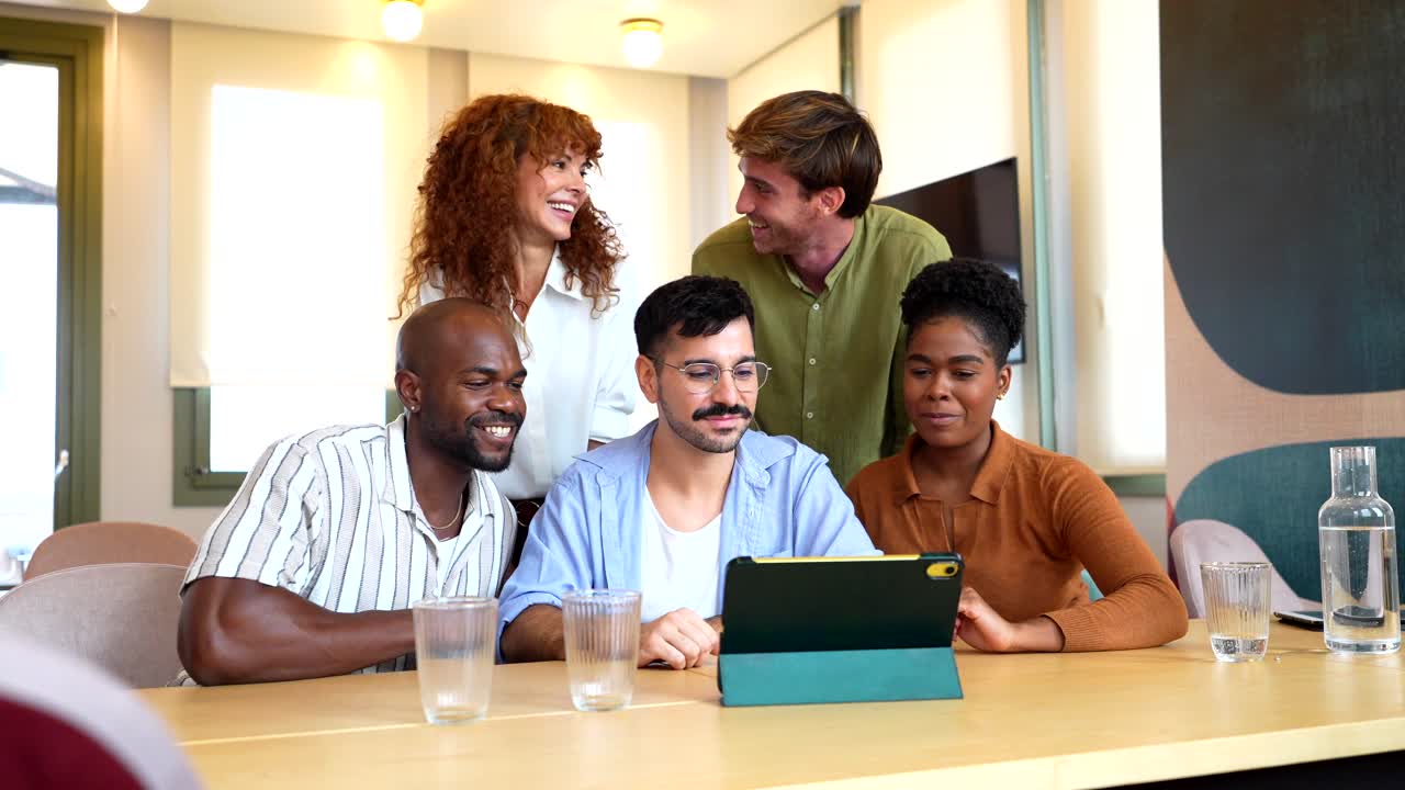 Groupe diversifié de collègues faisant signe de la main pendant un appel vidéo sur une tablette