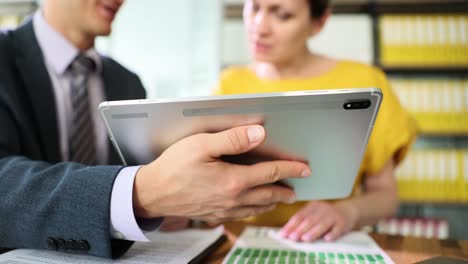 business professionals discussing data on a tablet in an office setting