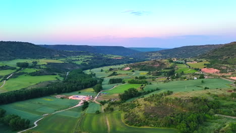 drone panning shot over green farmland in la alcarria, near brihuega, spain. the clip reveals cultivated fields, country roads, scattered houses and soft hills under calm morning light